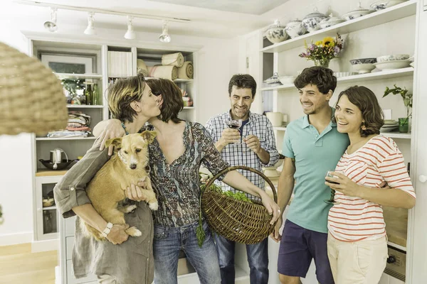 Cinco adultos amigos e cão saudação na cozinha — Fotografia de Stock