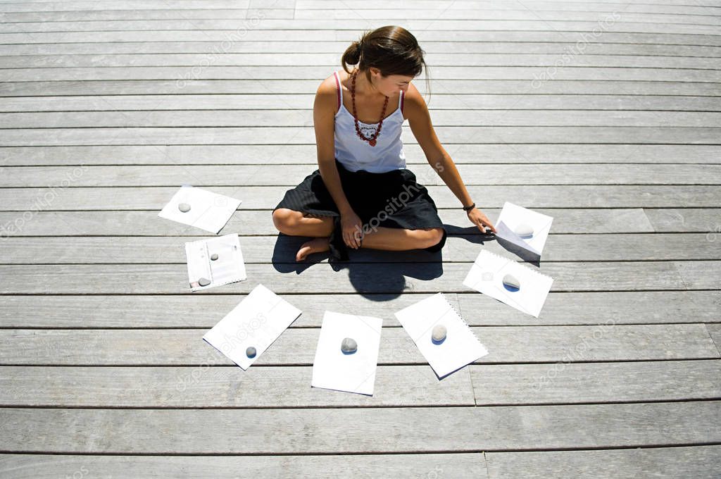 Woman sitting on decking with financial documents