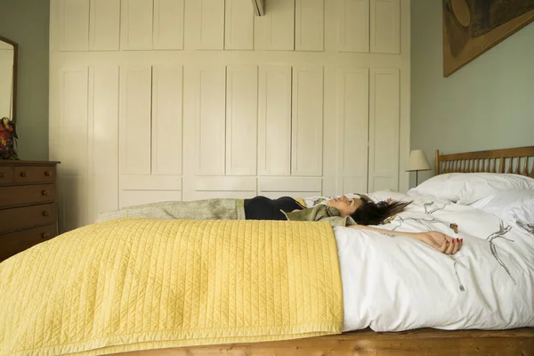 Vista lateral de la mujer acostada en la cama con los brazos abiertos —  Fotos de Stock