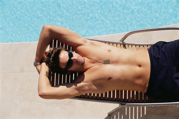 Man sunbathing by the pool