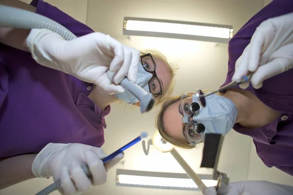 Dentista Enfermeira Dentária Inclinados Para Frente Segurando Equipamentos Odontológicos — Fotografia de Stock