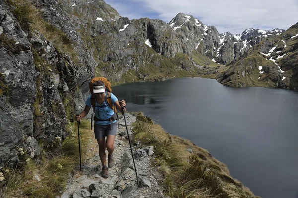 Woman hiking on path in mountains, New Zealand