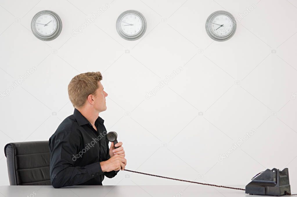 Businessman watching the clock holding telephone