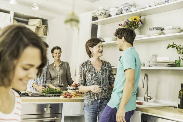 Pět dospělých přátel chatování a příprava jídla v kuchyni — Stock fotografie