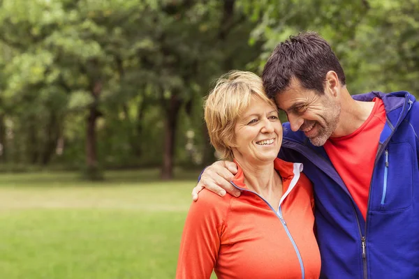 Couple Wearing Sports Clothing Outdoors Hugging Smiling — Stock Photo, Image