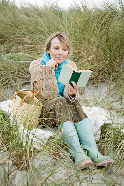 Woman reading a book on a dune
