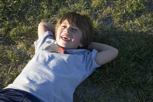 Portret Chłopca Leżącego Trawie Parku Śmiejącego Się — Zdjęcie stockowe