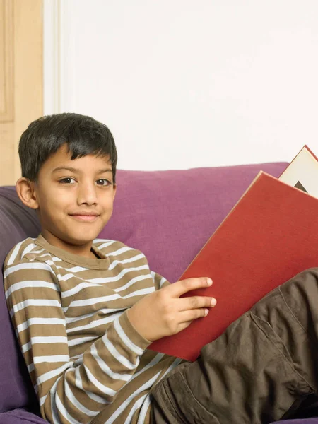 Boy Reading Book Sofa — kuvapankkivalokuva