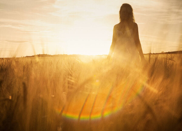 Young woman in barley field on sunset