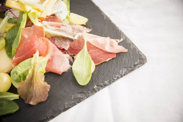 Presunto e folhas de salada em ardósia, close-up — Fotografia de Stock