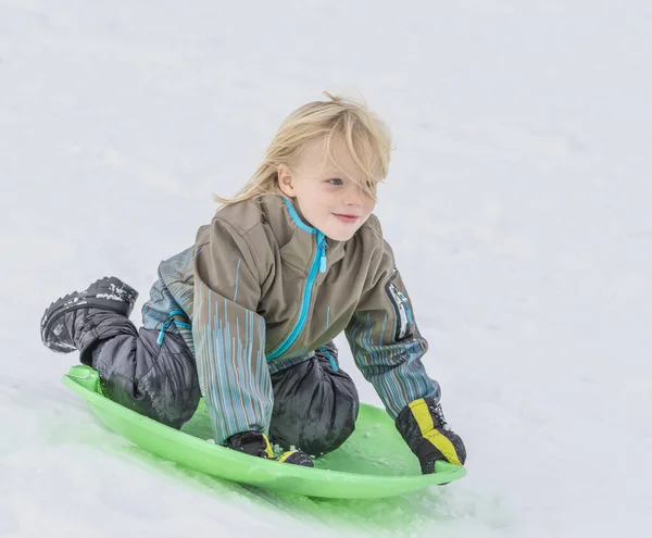 雪の中でトボガンで遊ぶ男の子 — ストック写真