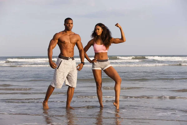 Couple sur la plage, muscles fléchissants, posant — Photo