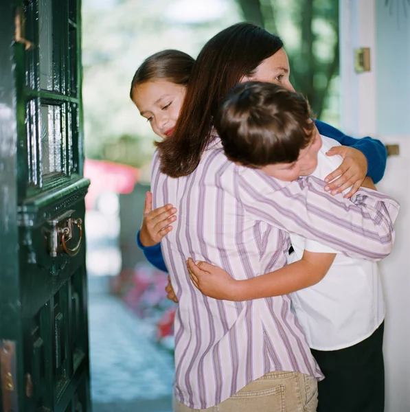 Moeder Knuffelen Haar Kinderen Deuropening — Stockfoto