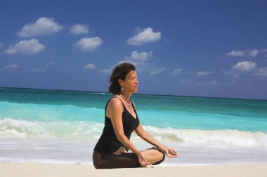 Plajda, Cennet Adası, Nassau, Bahamalar 'da, Lotus pozisyonunda olgun bir kadın.