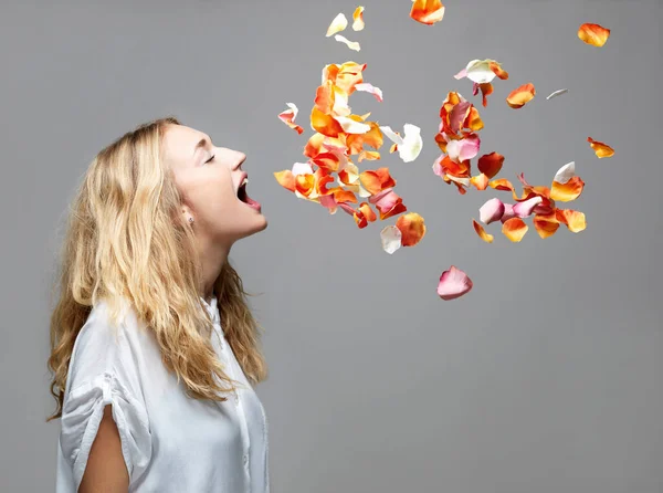 口の中に花弁が空中に浮かんでいる若い女性 — ストック写真