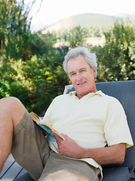 Senior man on sun lounger with book