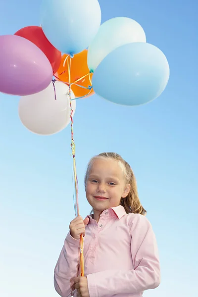 Young girl holding a bunch of balloons