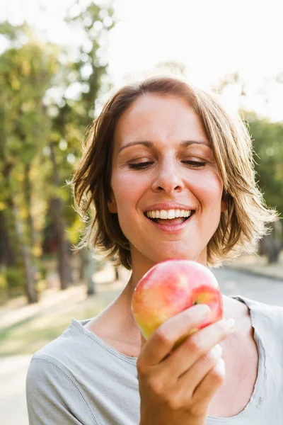 微笑的妇女吃苹果户外 — 图库照片