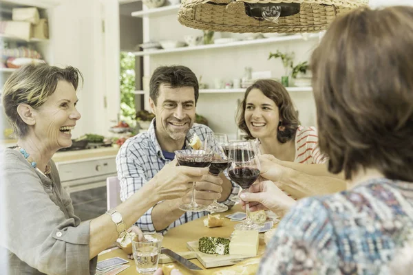 Взрослые друзья делают тост с красным вином за обеденным столом — стоковое фото