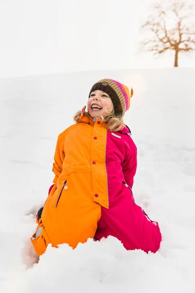 雪の上でひざまずいて雪のスーツを着た女の子の肖像画 — ストック写真