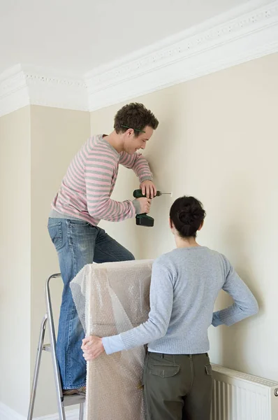 Couple drilling wall at home
