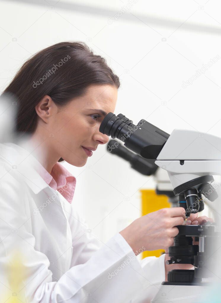 Scientist using microscope in lab