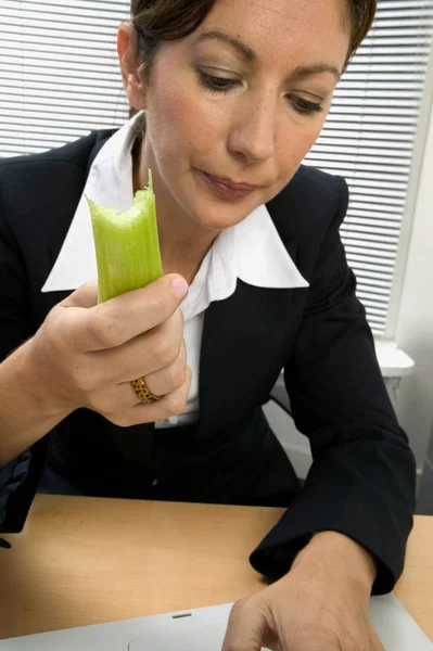 在办公室里吃芹菜的女商人 — 图库照片