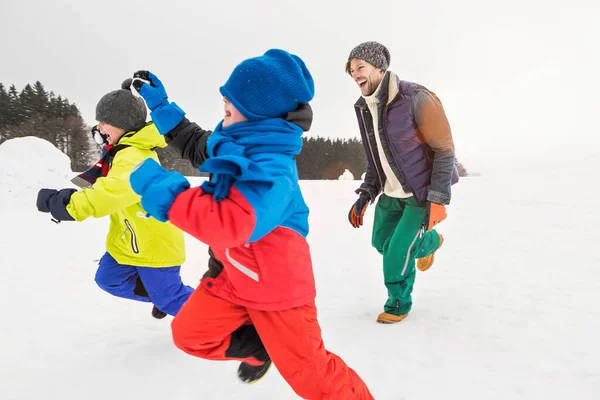 雪の中を走っている男と二人の少年 — ストック写真
