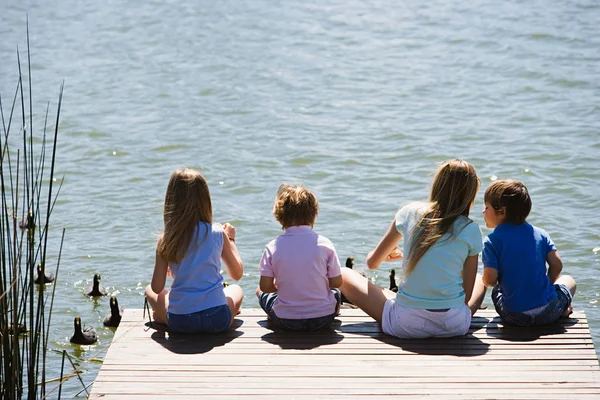 Bambini che nutrono anatre su un lago — Foto Stock