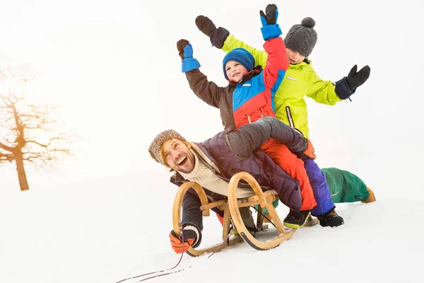 雪の中でトボガンの2人の男の子と男 — ストック写真