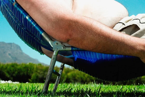 Overweight man sunbathing on grass