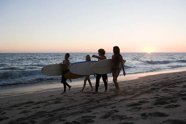 日落时冲浪者在海滩上散步 — 图库照片