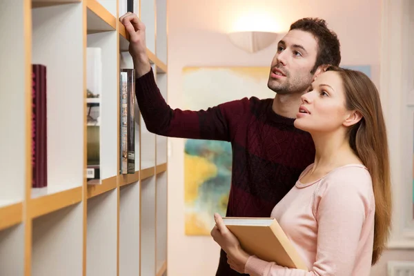 Junges Paar Wählt Buch Aus Bücherregal — Stockfoto