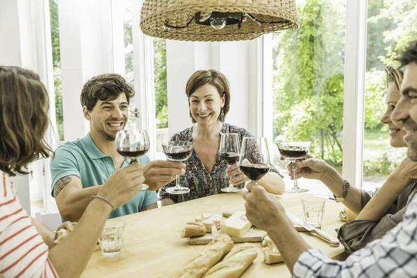 Пять взрослых друзей произносят тост за обеденным столом — стоковое фото