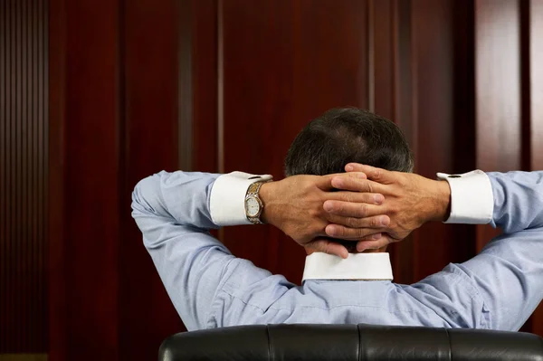 Businessman relaxing with hands behind head