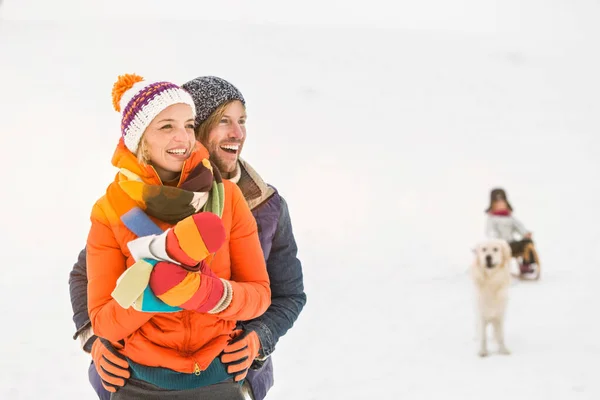 雪の中で女の子と犬を背景にカップル — ストック写真