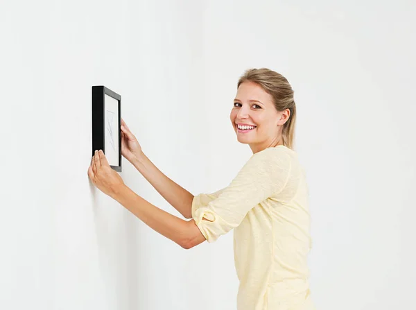 Young woman hanging picture on wall