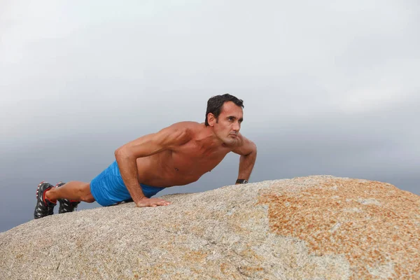 Hombre haciendo flexiones en la roca — Foto de Stock