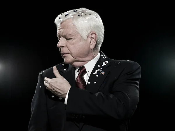 Politician covered in confetti isolated on black background