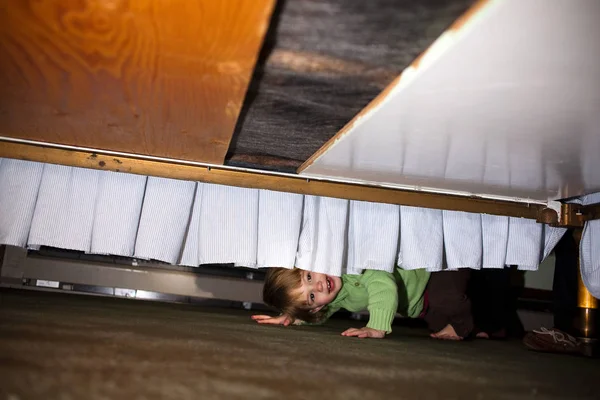 躲在床底下的小女孩 — 图库照片