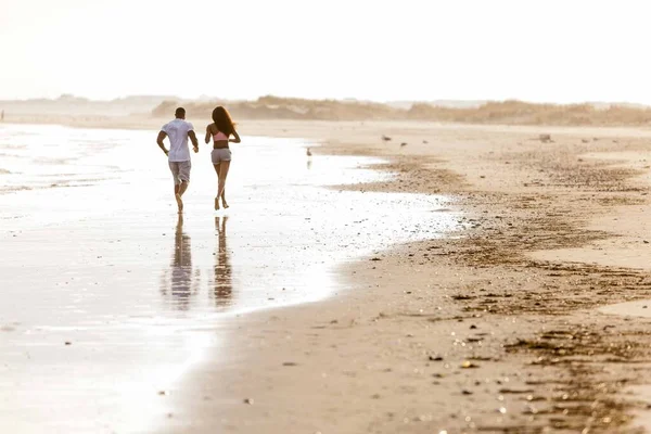 Pareja corriendo a lo largo de la playa, vista trasera — Foto de Stock