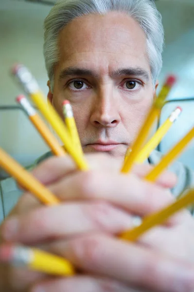 Man holding pencils in office
