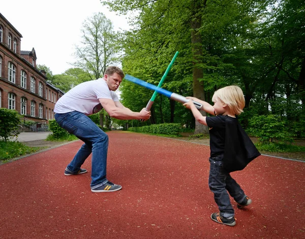 Father and son play fighting with toy swords