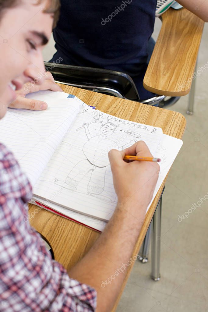 Male high school student doodling in notebook