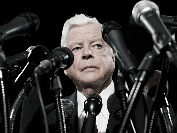 Politician and microphones isolated on black background