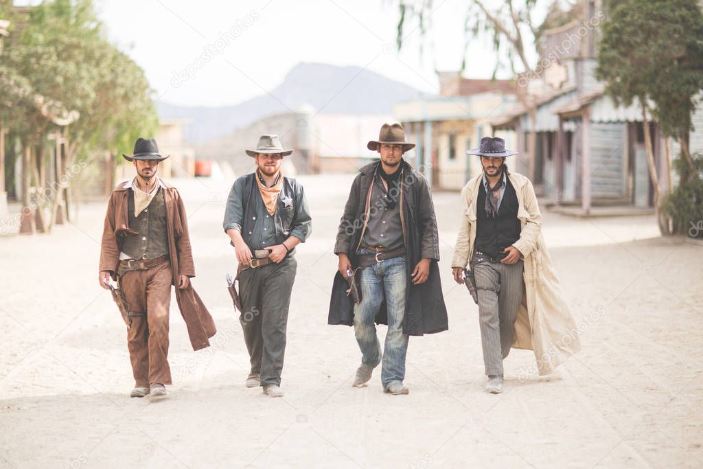 Portrait of four cowboys walking along street on wild west film set, Fort Bravo, Tabernas, Almeria, Spain