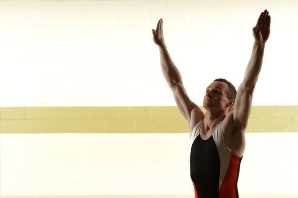 Мужчина гимнаст стоит с поднятыми руками — стоковое фото