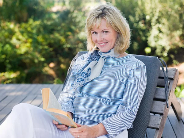 Mature woman on sun lounger with book
