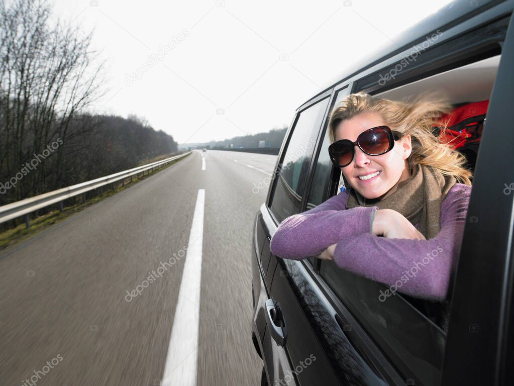 Young woman leaning out of car window