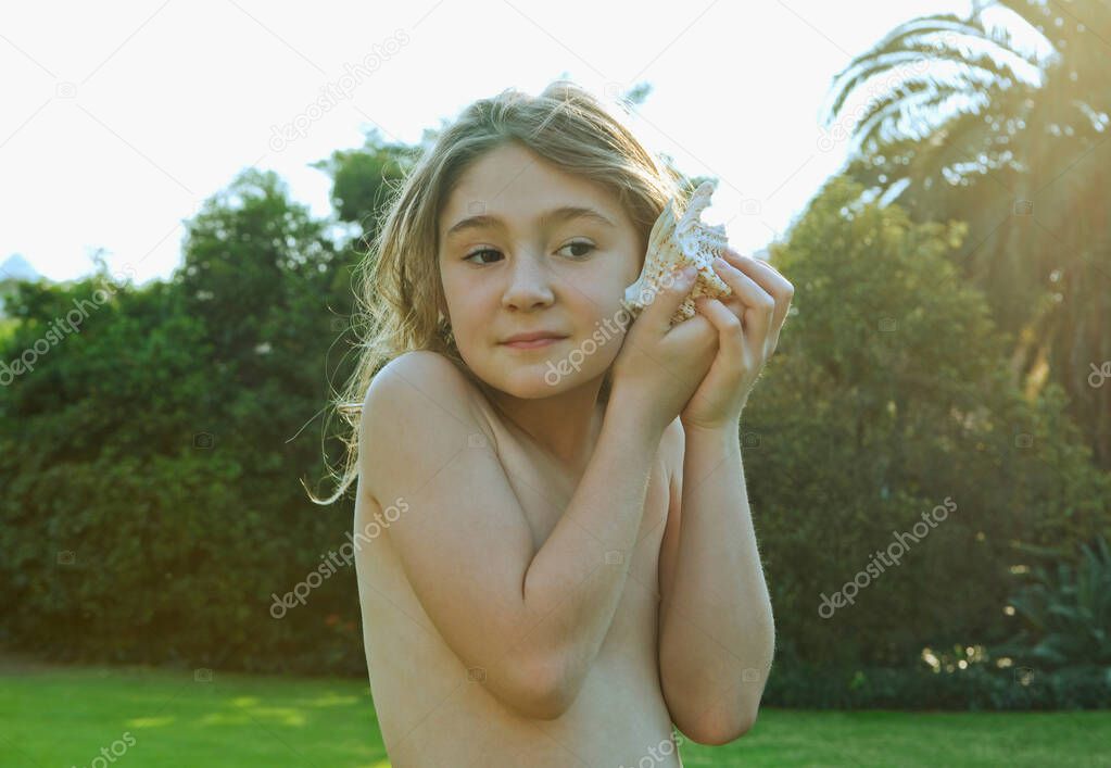 Girl holding shell to ear